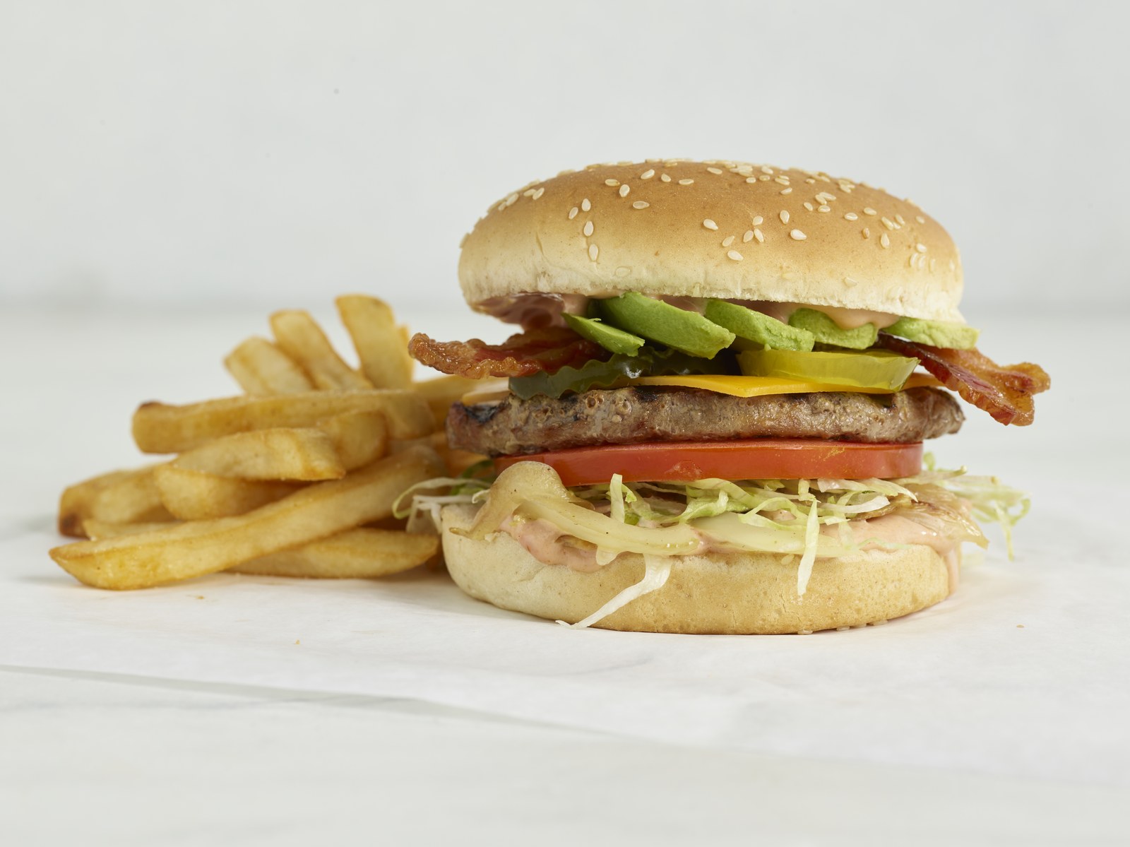 Avocado Bacon Cheeseburger with bacon, fresh avocado, cheese, tomato, pickles and a side of French fries