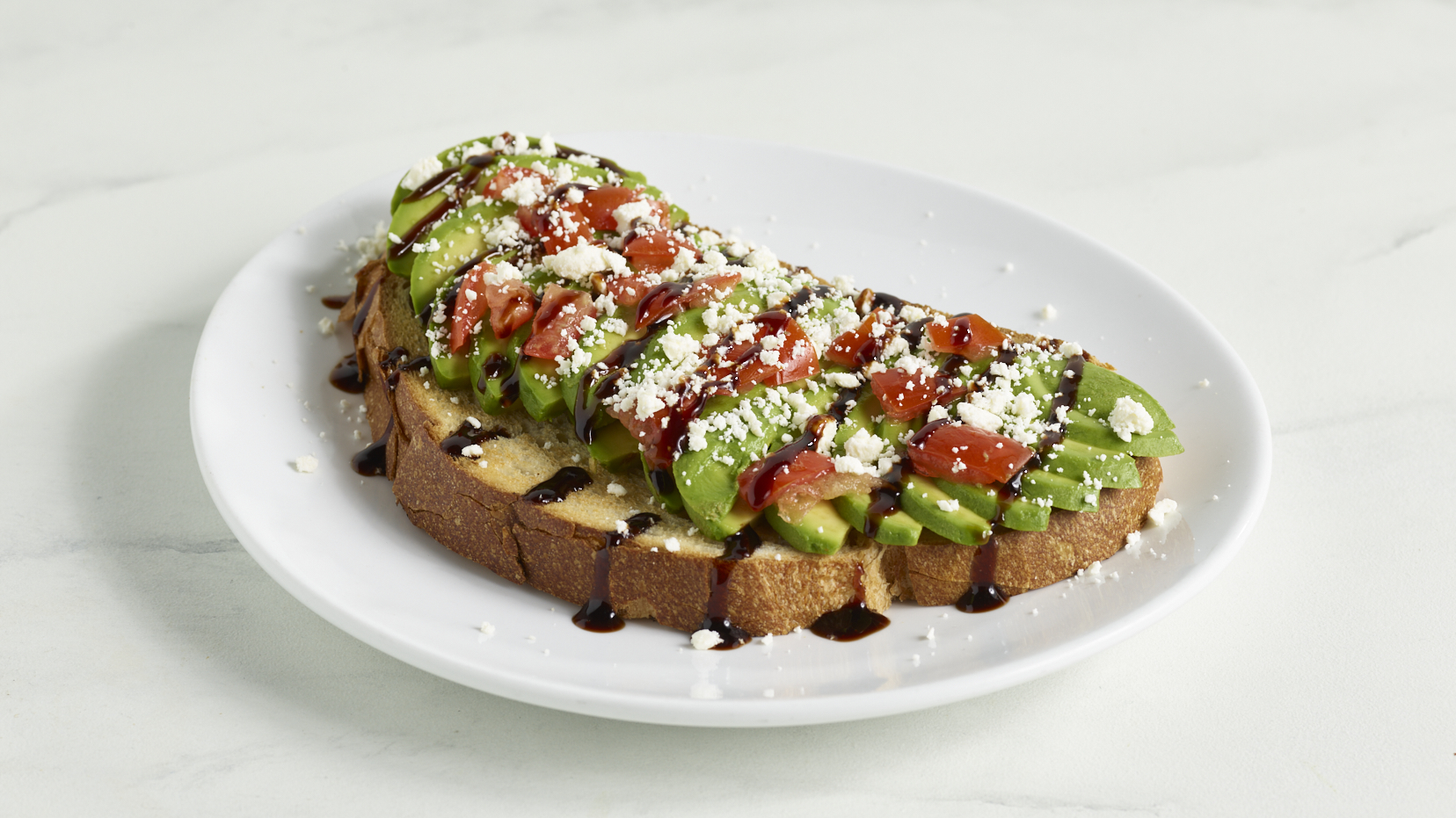 Avocado Toast on sourdough with tomatoes, feta, balsamic glaze and chili flakes