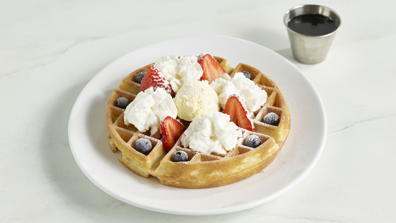 Belgian Waffle topped with whipped cream, vanilla ice cream, strawberries, blueberries and powdered sugar