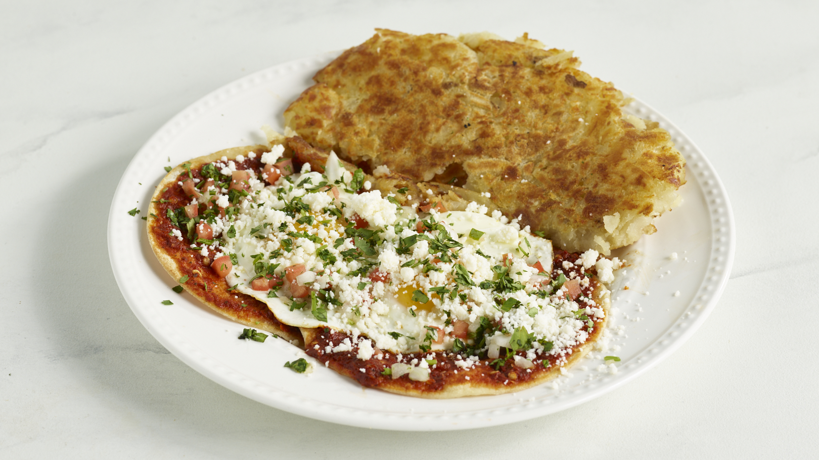 Huevos Rancheros on corn tortillas with red salsa, queso fresco, cilantro and crispy potatoes